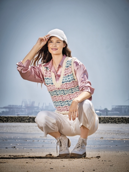 Pastellfarbener Strickpullunder, gestreift, über rosa Bluse, kombiniert mit weißen Caprihosen und hellem Hut.