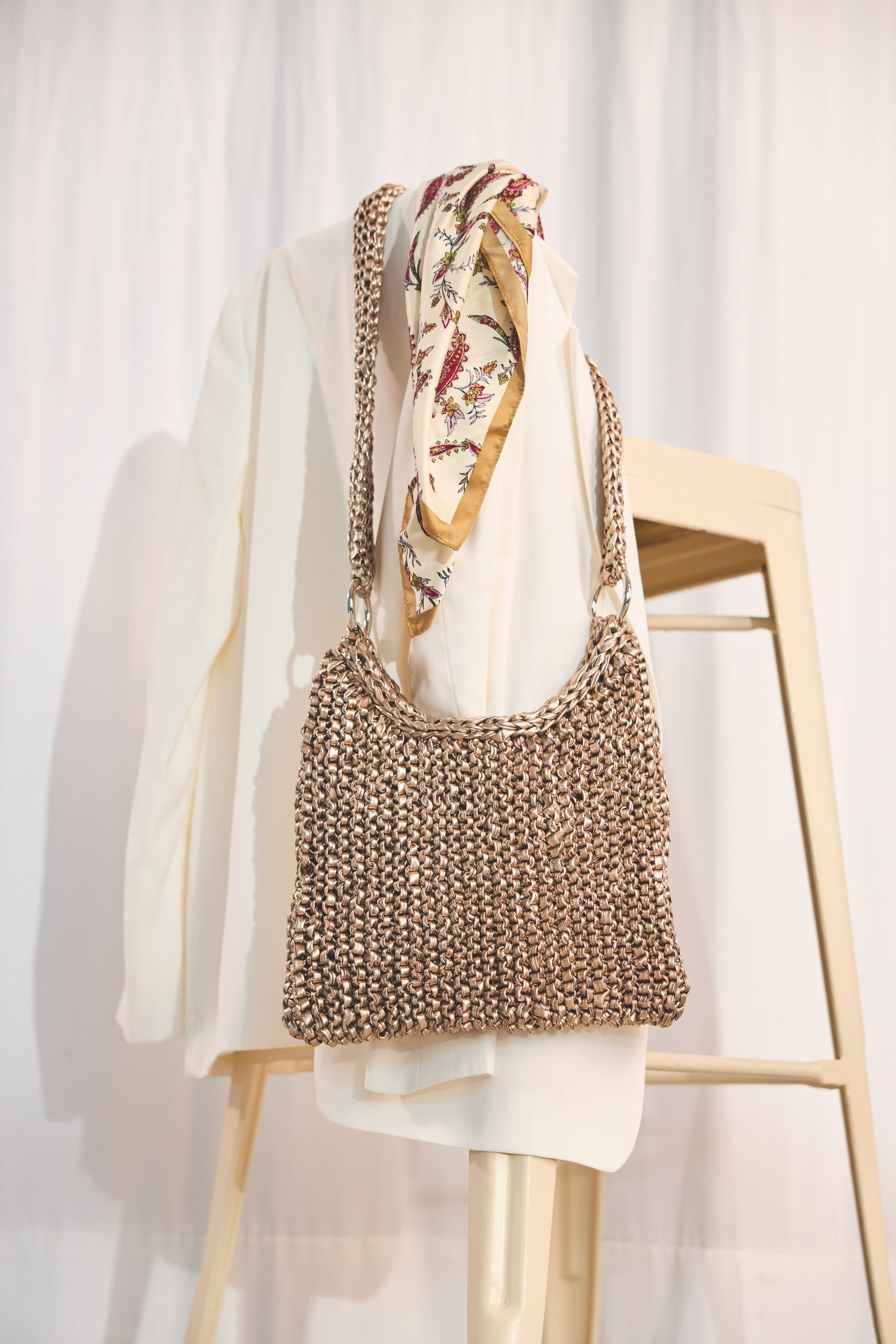 Gehäkelte, handgemachte Tasche in Erdtönen, cremeweißer Blazer, florales Tuch – modisch, einzigartig.