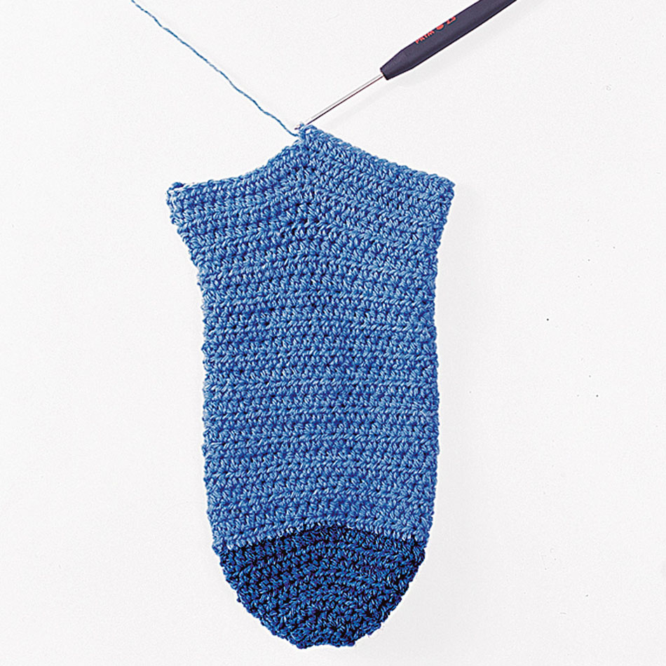 Handgefertigte, zweifarbige, blaue Socke mit feinem Häkelmuster. Modisch und DIY.