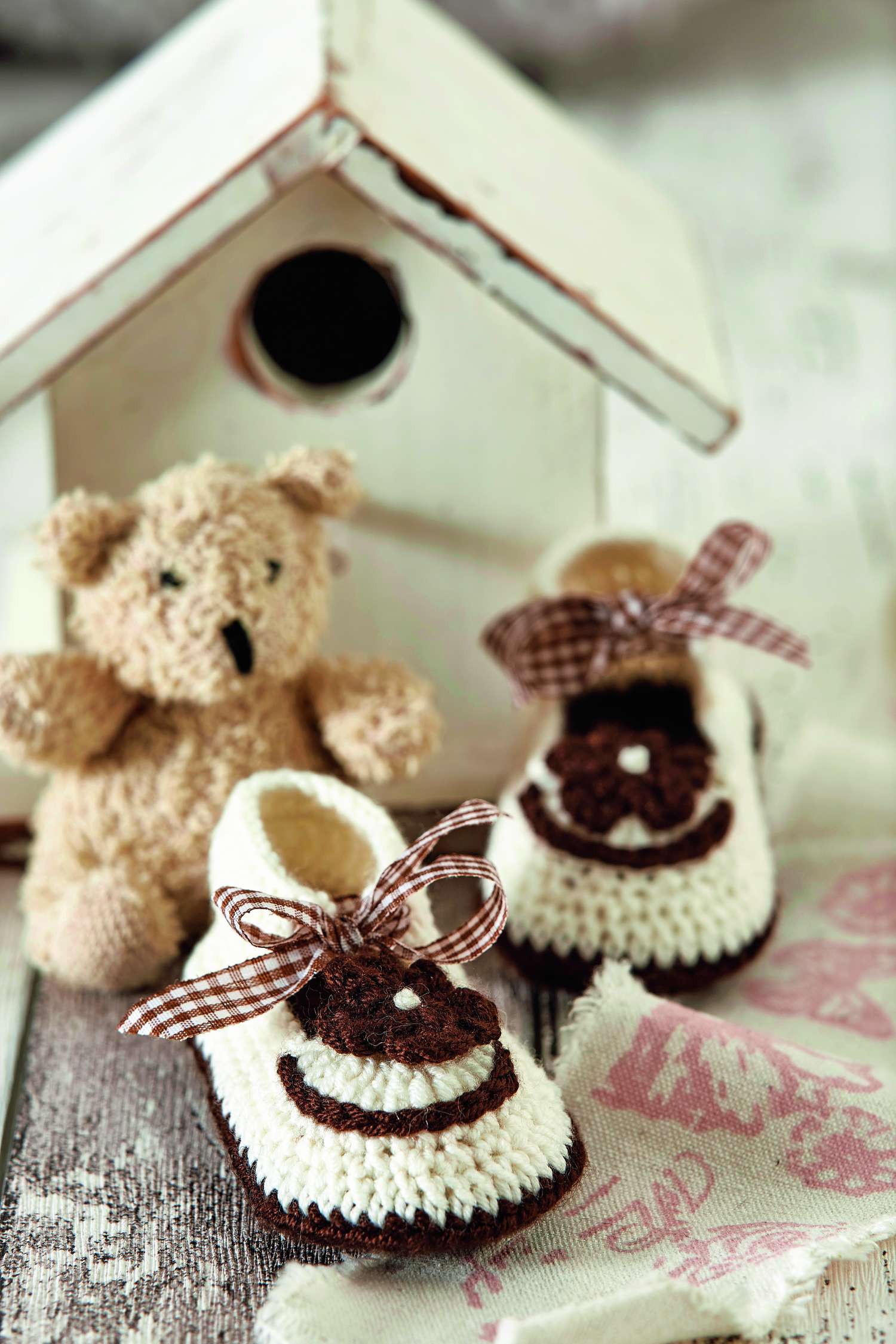 Weiße, handgestrickte Schuhe mit braunen Akzenten und karierten Schleifen. Modisch, DIY.