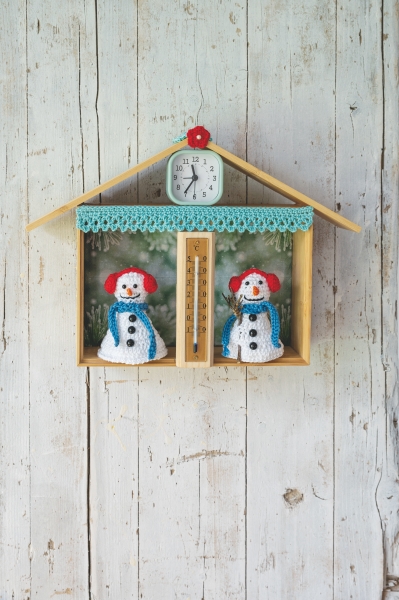 Bunte, handgemachte Schneemänner in gestrickter Kleidung, mit Uhr- und Thermometergehäuse im Hausdesign. DIY.