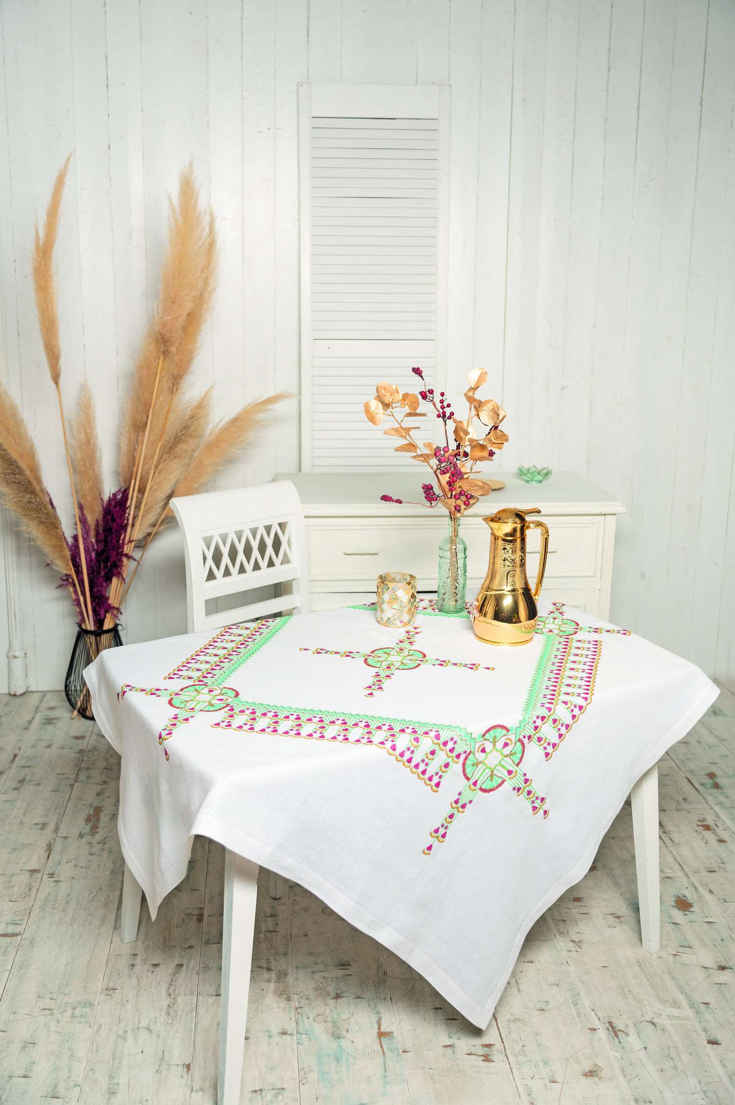 Weiße Tischdecke mit bunten, handgemachten Mustern und grünen Akzenten. Modischer Hingucker.