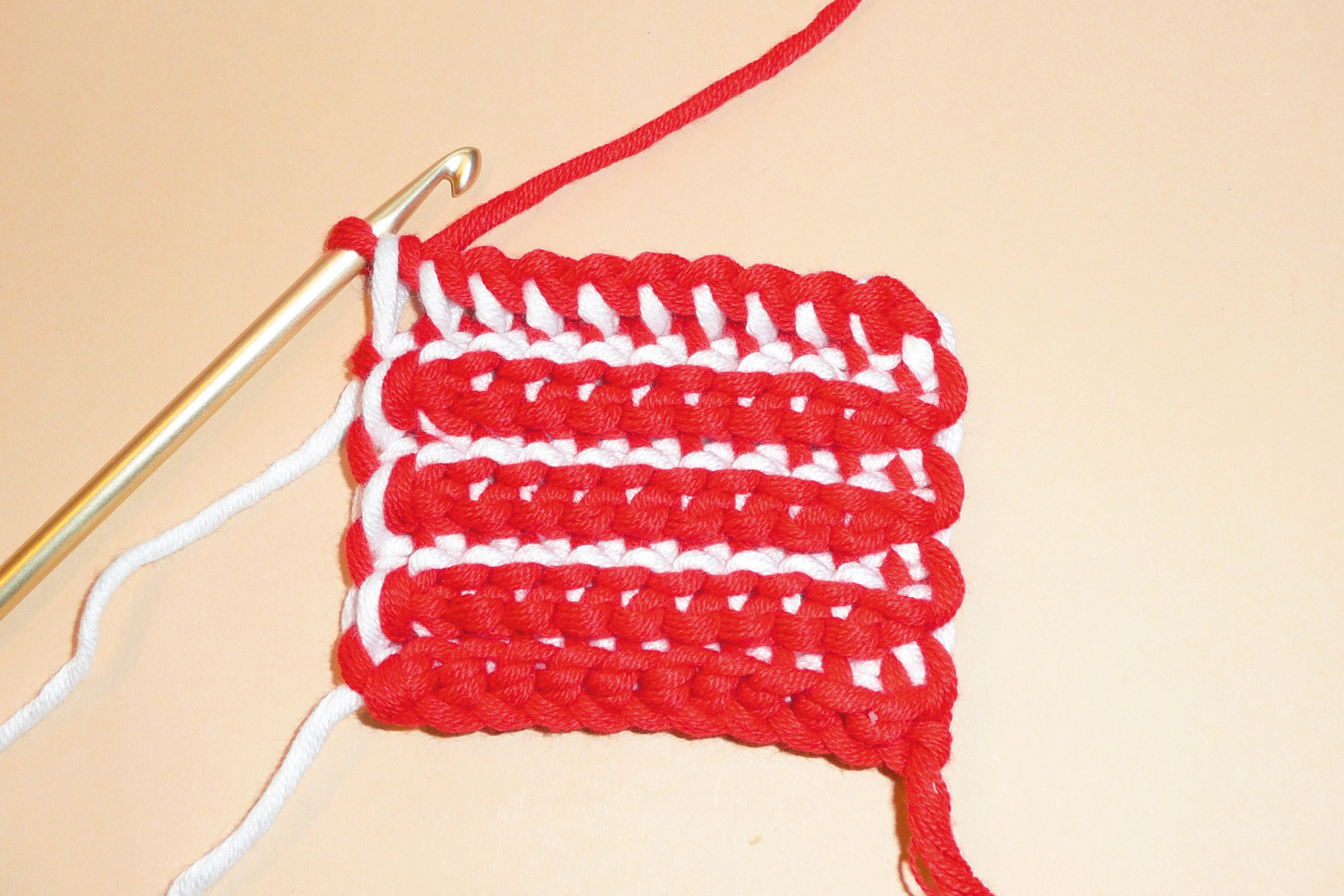 Rotes und weißes gehäkeltes Muster; DIY, handgefertigt, Streifen-Design, mit Häkelnadel.