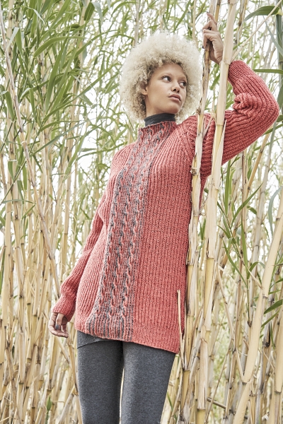 Coralfarbener, langer Strickpullover mit Zopfmuster. Modisch, handgemacht, DIY-Chic. Kombiniert mit dunklen Leggings.