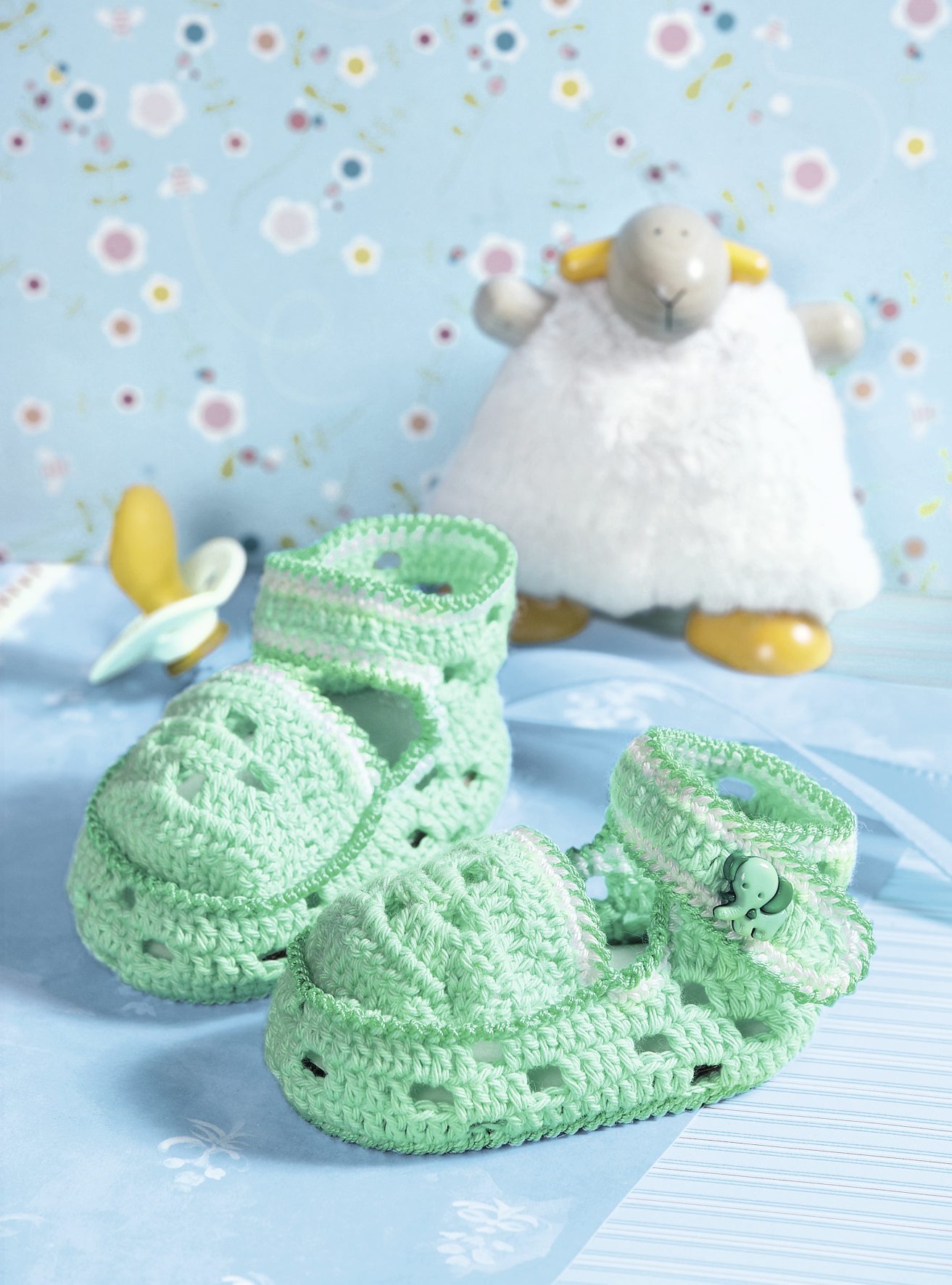 Mintgrüne, gehäkelte Babyschuhe, kunstvoll und sorgfältig gearbeitet, DIY und handgefertigt mit süßem Knopfdetail.