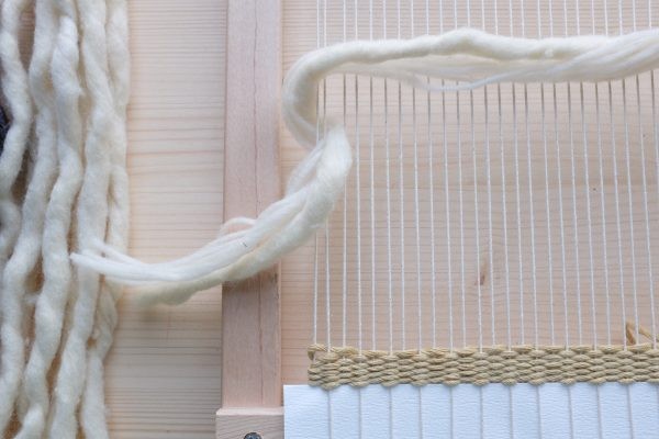 Naturfarbene Garne auf Holzwebrahmen; diy, handgefertigt, kunstvoll verflochten, weiche Textur, minimalistisch.