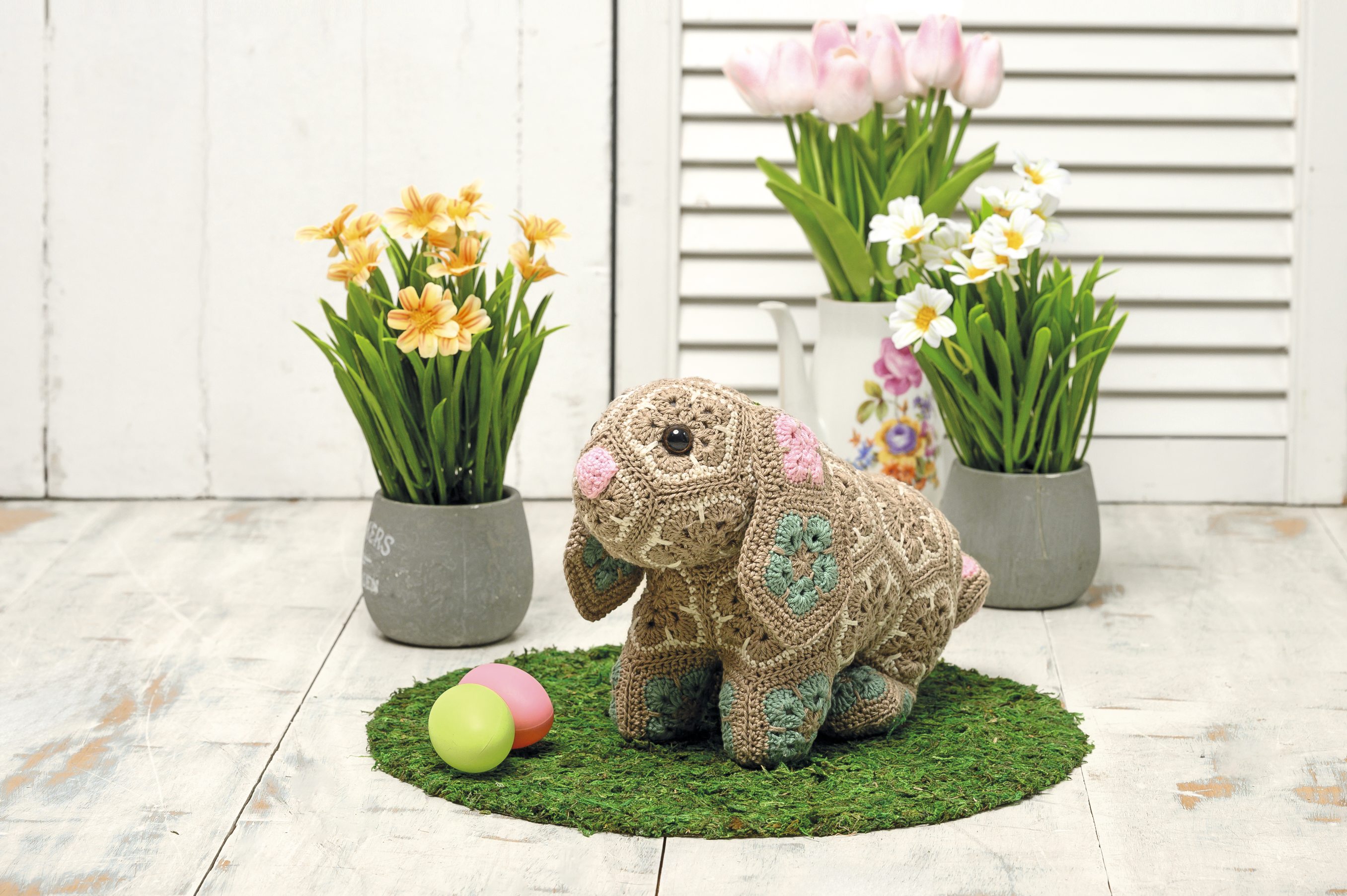 Handgemachter Hase aus beigem Garn, bunte Muster. Pastelltöne. DIY, Kunsthandwerk, süßes Design.