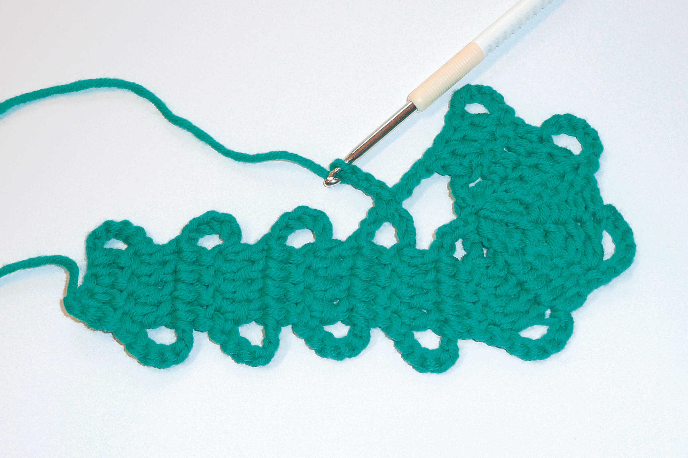 Handgefertigtes, grünes Häkelmuster mit Bohnenmuster. Lebendige Farbe, DIY-Charme. Handarbeit trifft auf Stil.