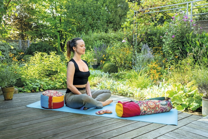 Schwarzes Top, graue Hose; bunte, handgemachte Kissen mit Mustern. Modisch und bequem für Yoga.