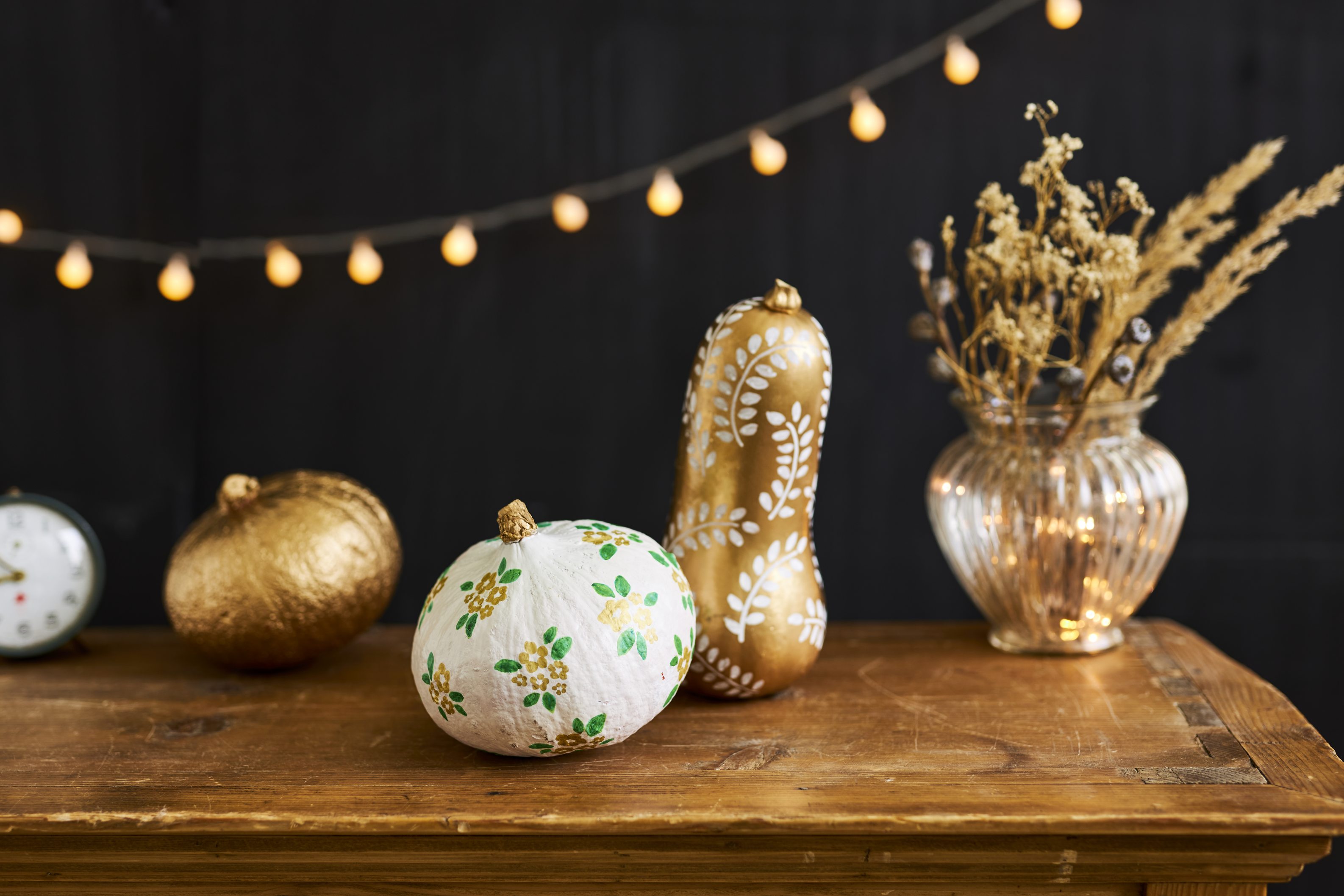 Goldene und weiße Kürbisse, handbemalt mit Blumen- und Blattmustern; DIY, kunstvolle Herbstdeko.
