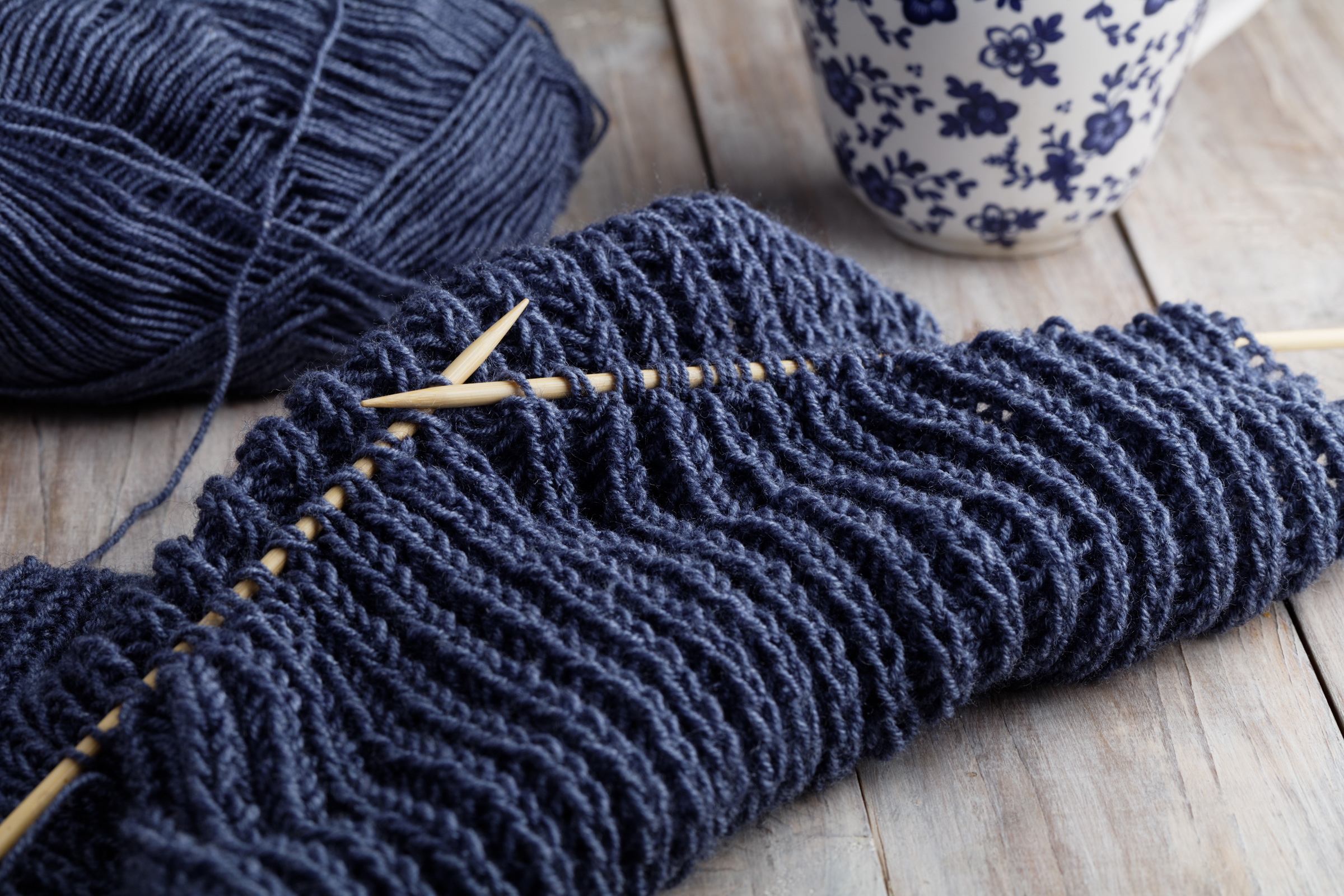 Modisch gestricktes Projekt in tiefem Blau. Dichtes, geripptes Muster, selbstgemacht mit Holzstricknadeln.