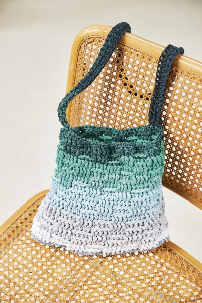 Dreifarbige, gehäkelte Tasche in Grün- und Grautönen. Modisches DIY-Stück mit grobem Maschenmuster.