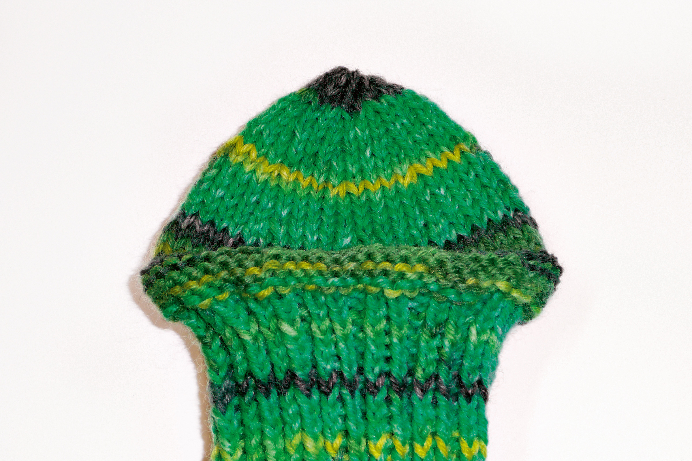 Handgemachte grüne Mütze mit gelb-schwarzen Streifen. Modisches Muster, perfekter DIY-Stil.