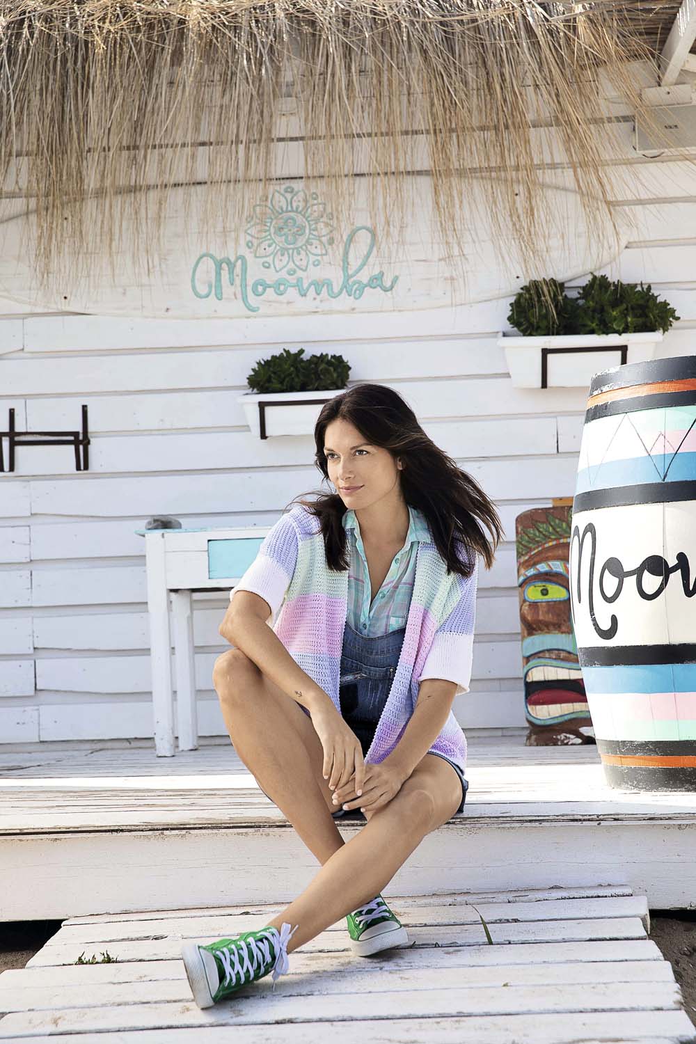 Gestreifter, modischer Cardigan in Pastell; blaues Hemd, Denim Overall; auffällige grüne Sneaker.