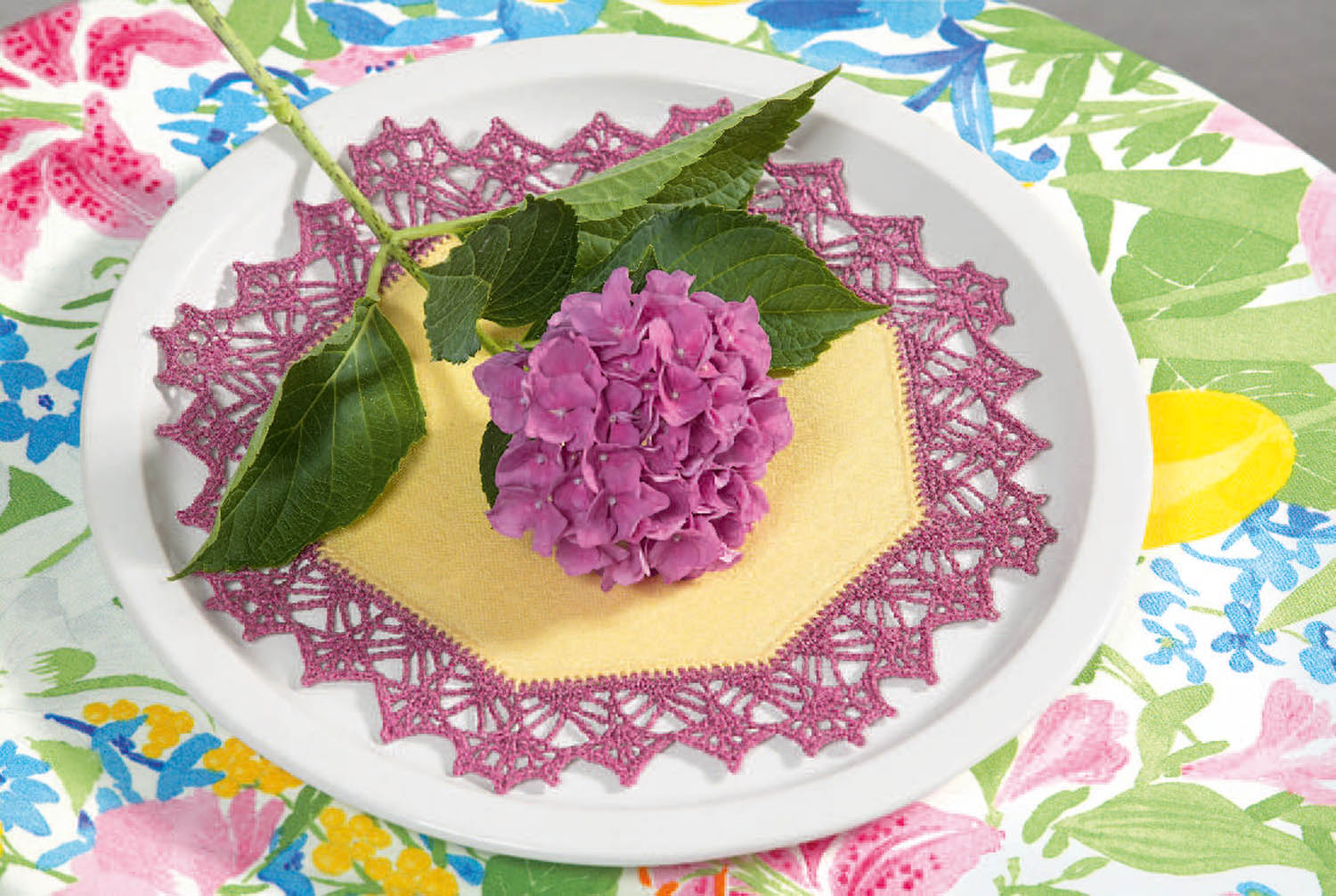 Gelbes Tuch mit lila Spitzenrändern, handgearbeitet; modisch verziert mit blühender Hortensie.