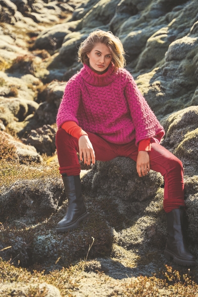 Pinkes Oversize-Kabelstrick-Poncho, rote Jeans, schwarze Stiefel; modisch, handgemacht, trendige Farben.