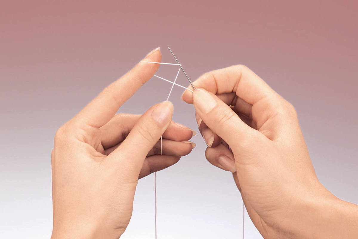Fingerspitzengefühl beim Fädeln einer Nadel. Handarbeit, DIY, präzise Handbewegung.
