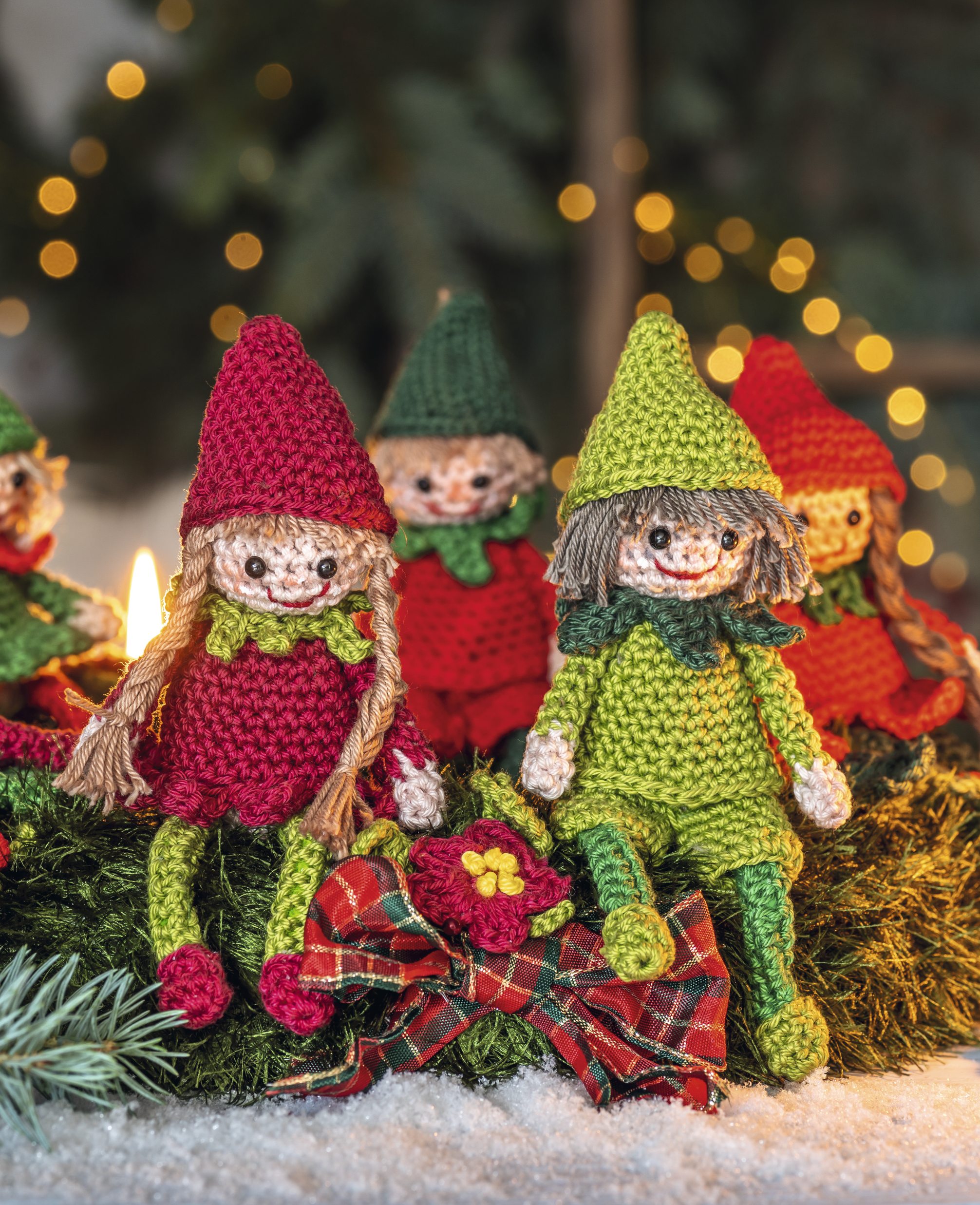 Bunte gestrickte Wichtelpuppen in Rot und Grün, liebevoll handgefertigt mit detailreichen Mustern.