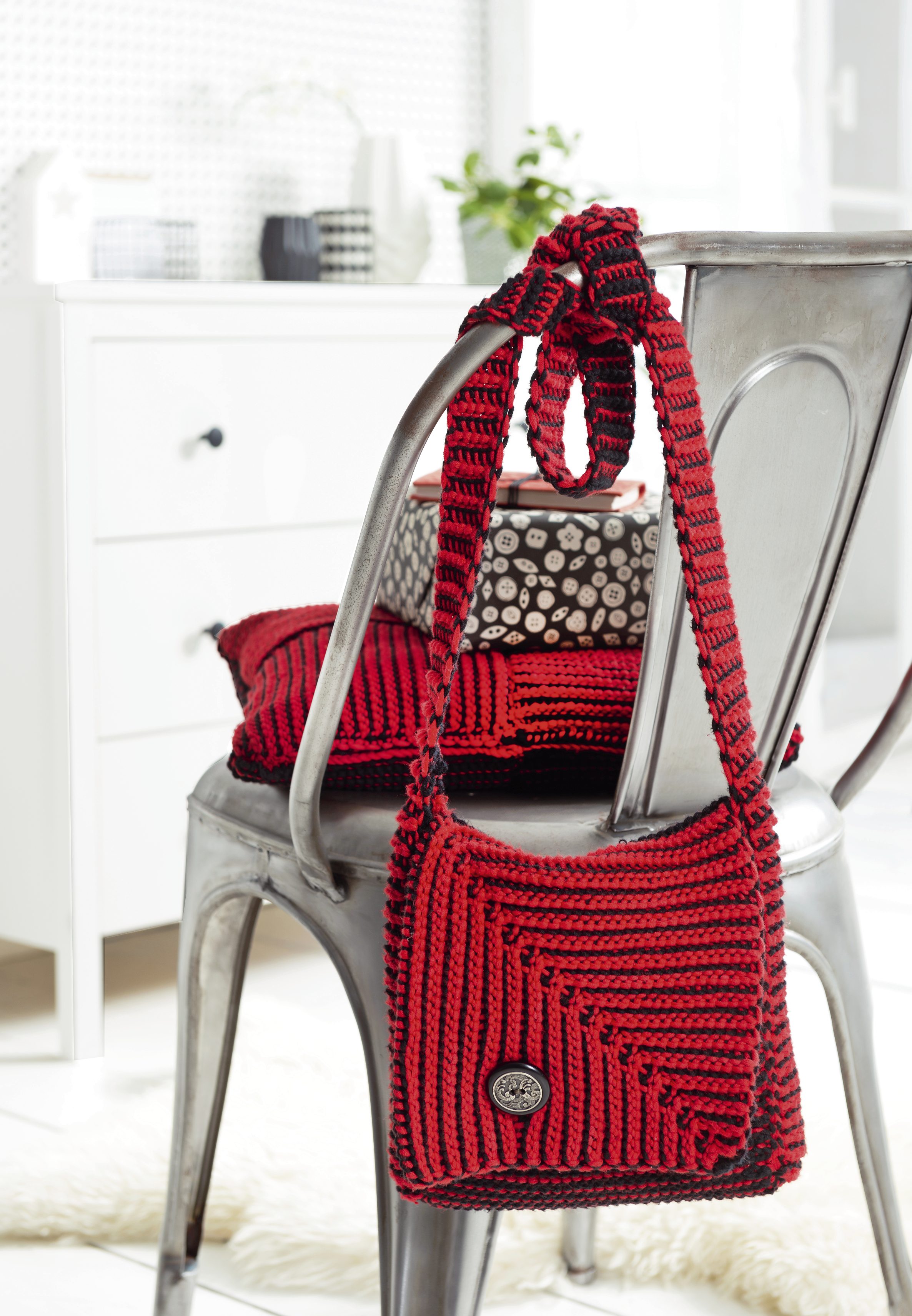 Modische, handgemachte Tasche aus rot-schwarzer Wolle. Streifenmuster im diagonalen Schnitt mit dekorativem Knopf.