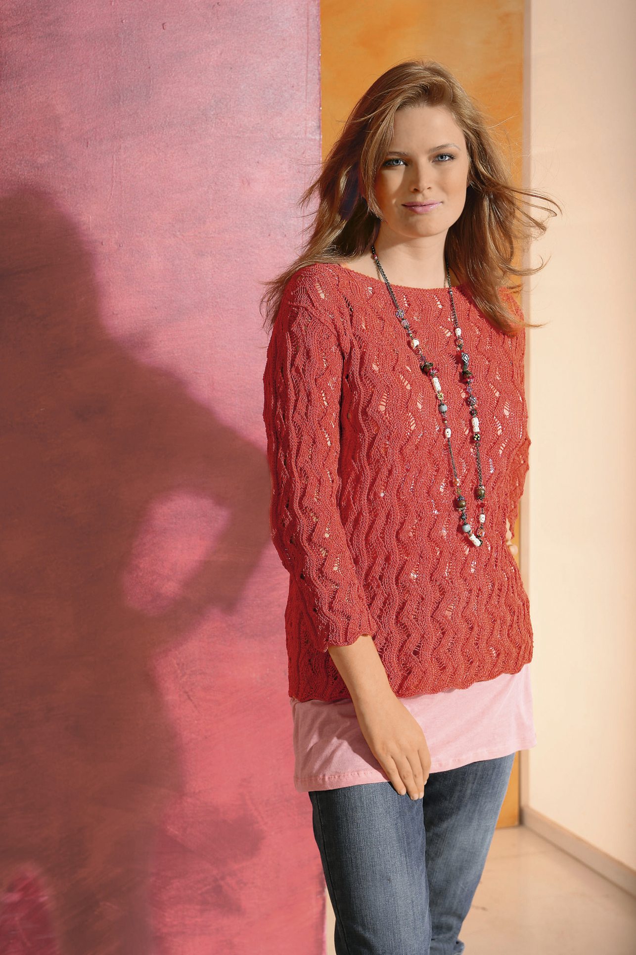 Roter Strickpullover mit Zopfmuster, lässiger Schnitt, diy-Look, kombiniert mit langer Kette und Jeans.