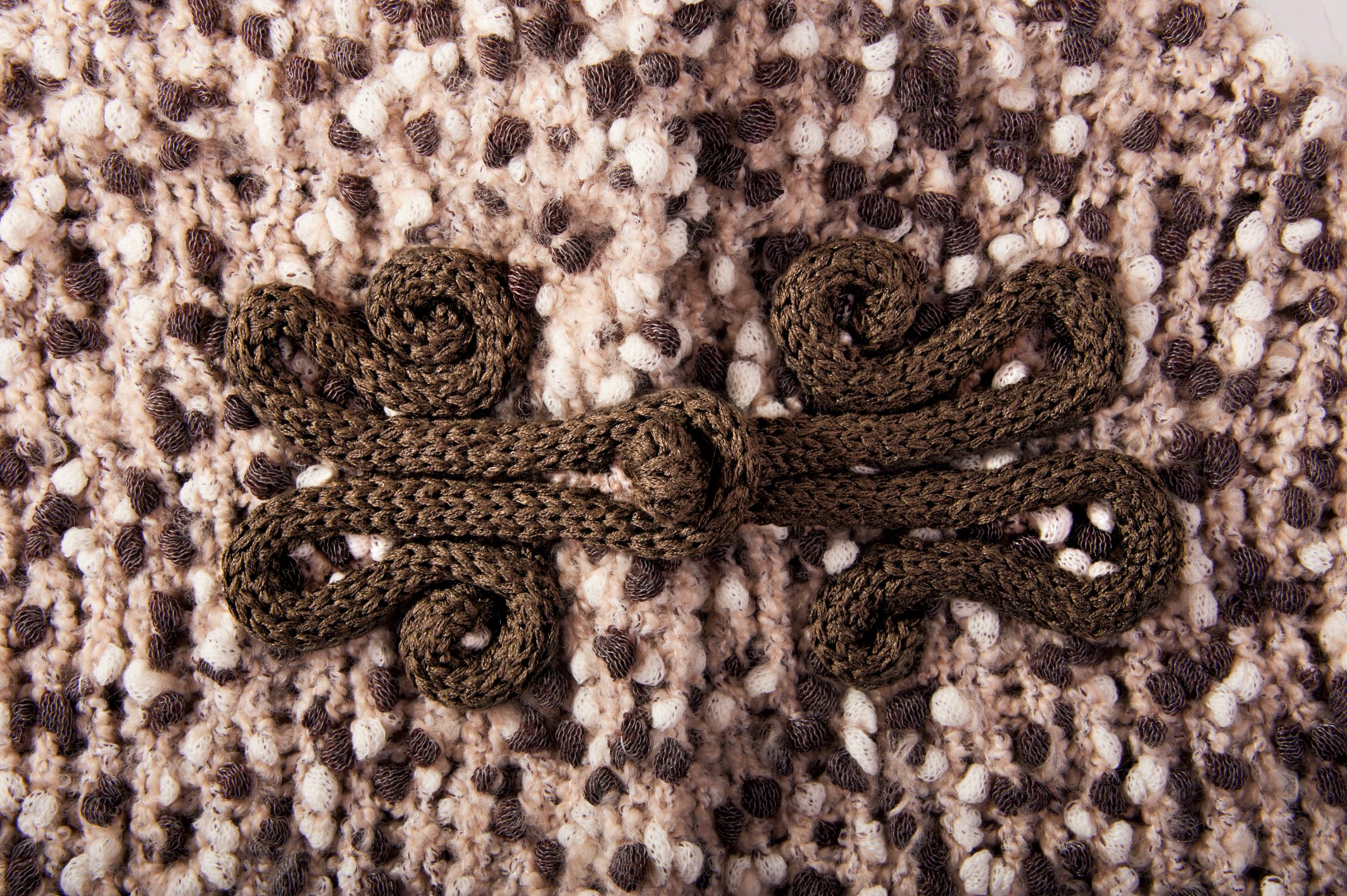 Braune, handgemachte Knopfverzierung auf gestricktem Stoff in Beige- und Brauntönen. Modisches DIY-Design.