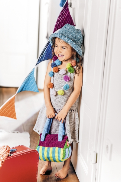 Häkelkleid in Grau mit bunter Pompon-Kette, gestreifte Tasche, blauer Hut. Modisch, handgemacht.