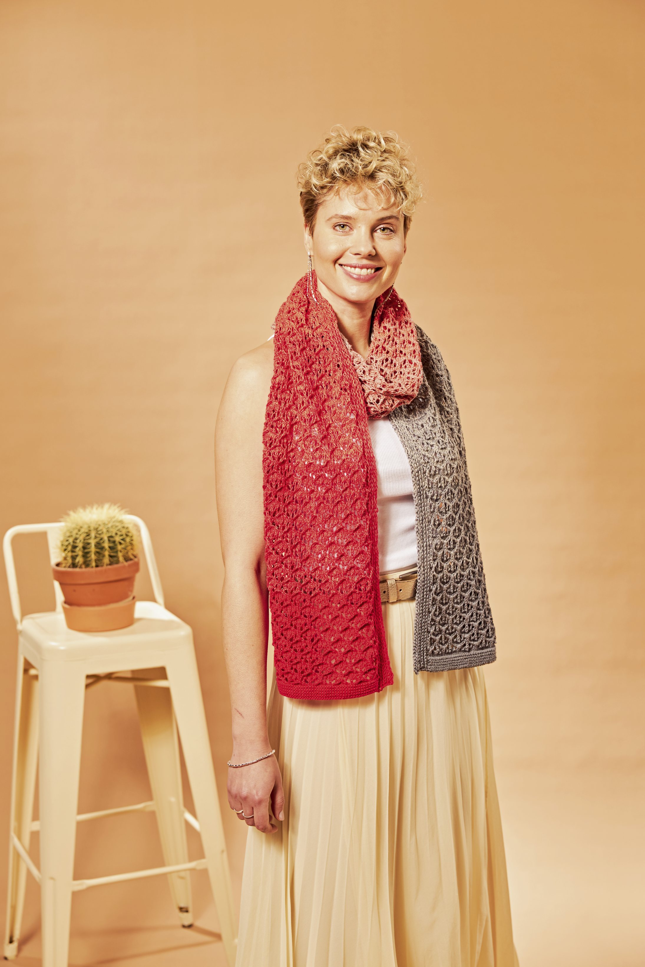 Roter und grauer DIY-Schal, handgestrickt mit feinem Lochmuster. Modisch und elegant über weißem Top.