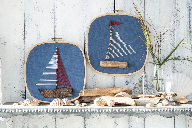 Fadenkunst mit Segelbooten, blaues Textil, naturbelassene Holzdetails, handgemacht, maritimer DIY-Stil.