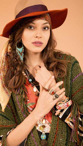 Modisches Boho-Outfit: Grün gestrickter Mantel, buntes Kleid, breite Hüte, gemusterte Accessoires, Handarbeit.