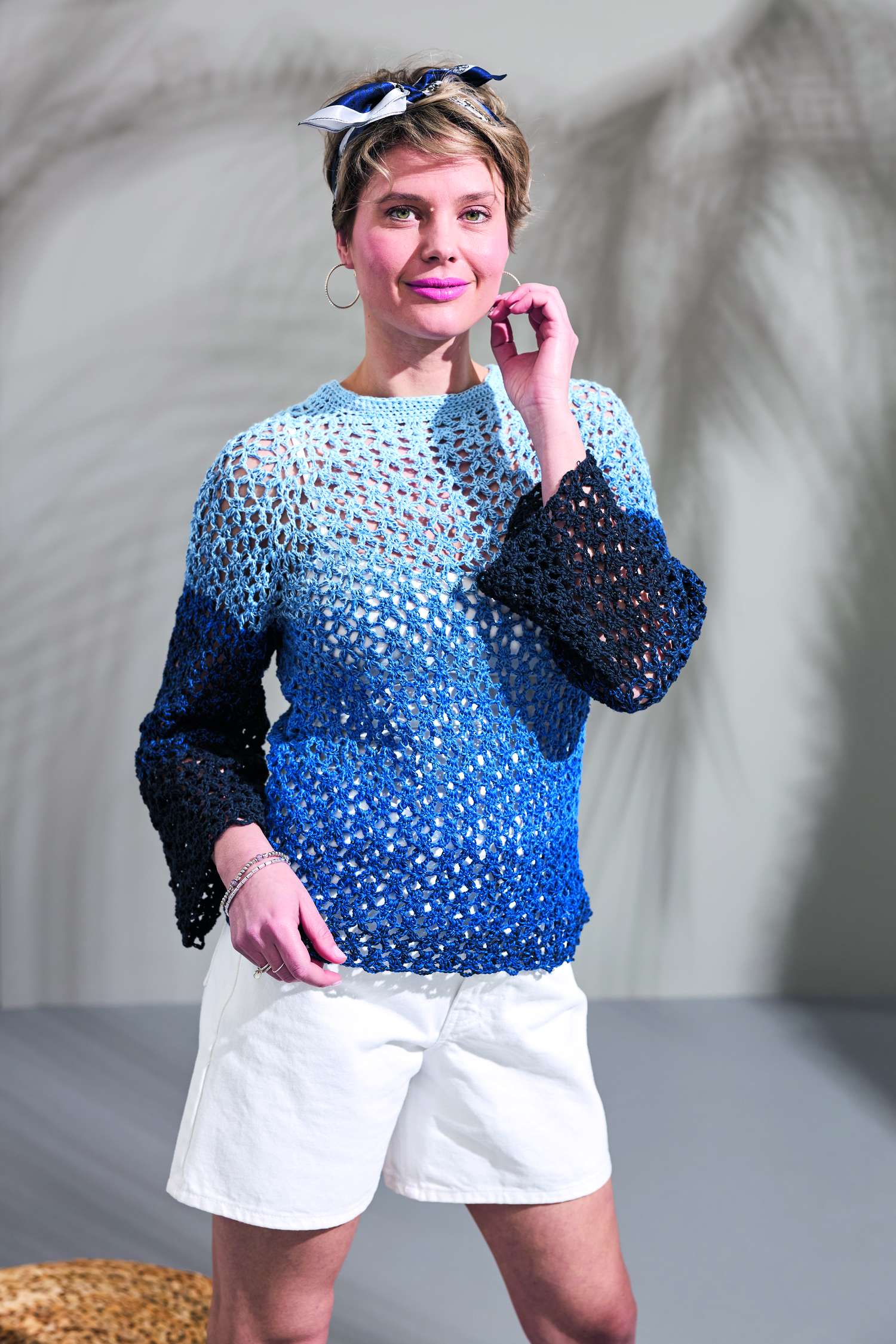 Selbstgemachter Häkelpullover in Blauverlauf, luftiges Muster, kombiniert mit weißer Hose; modisch, einzigartig.