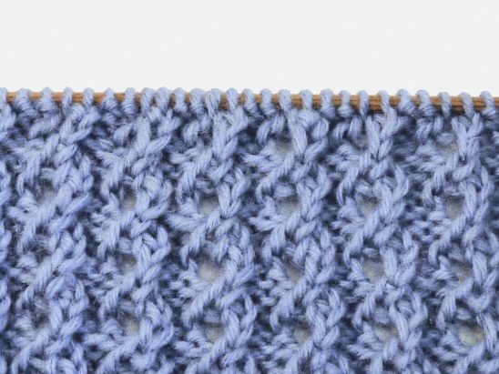Hellblaue, handgemachte Strickarbeit mit detailliertem, modischem Muster. DIY-Stil, kunstvoll und kreativ.