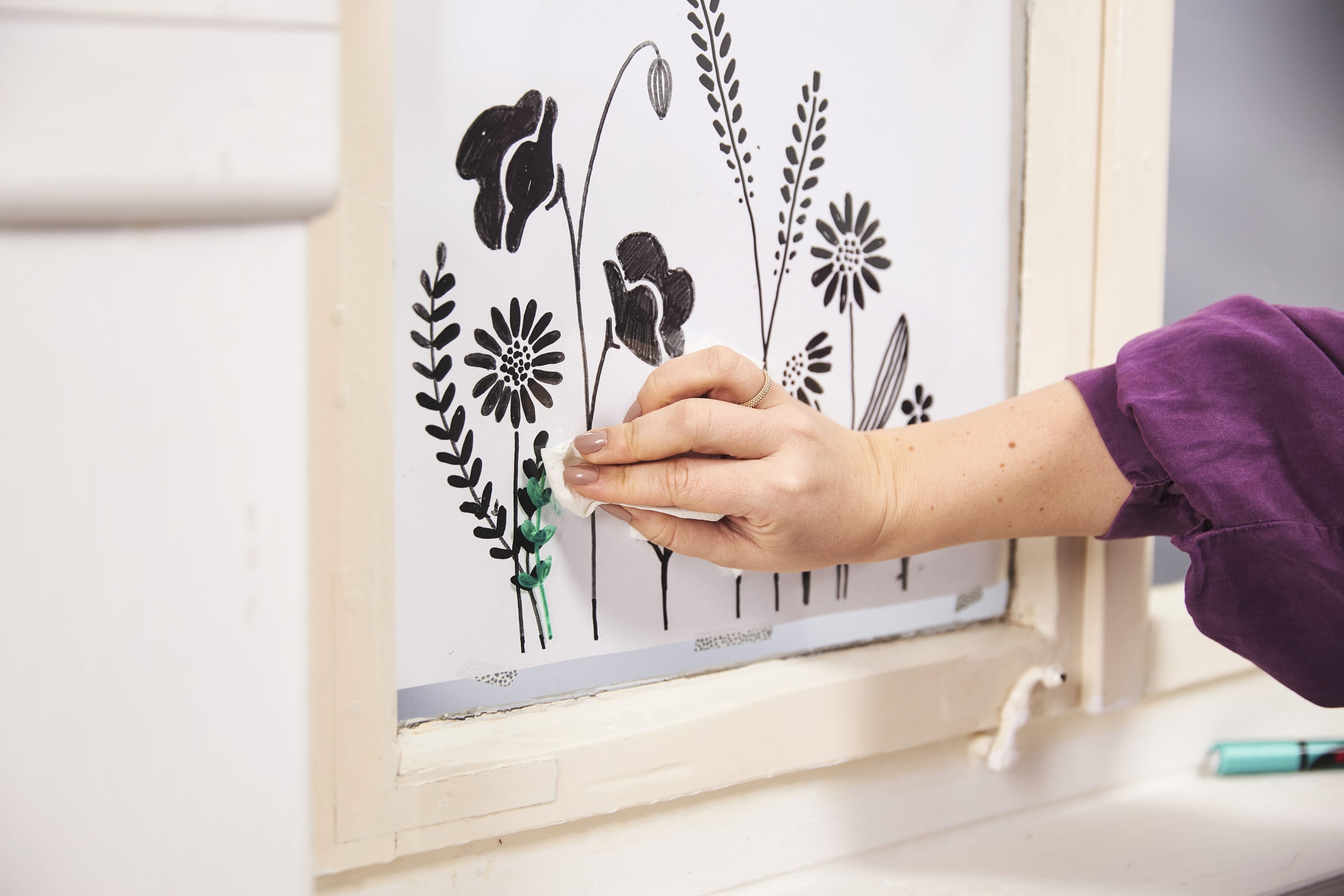 Handgemalter floraler Druck in Schwarz auf weißem Hintergrund, lila Ärmel betont die künstlerische Sorgfalt.