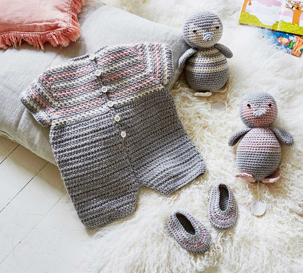 Grau-rosa gestrickter Babystrampler mit Knöpfen, passendem DIY-Spielzeug und Schuhen. Modisch und handgemacht.