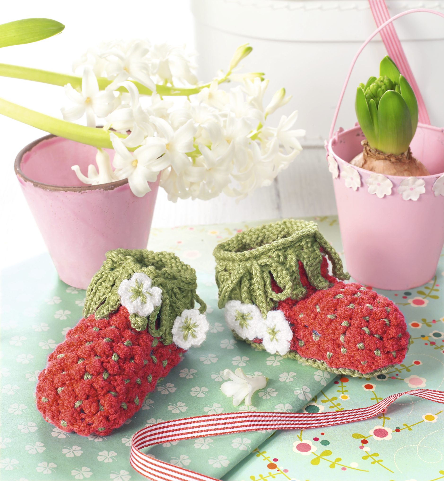 Handgemachte, rot-grüne Babyschuhe in Erdbeer-Optik mit verspieltem Blütenmuster. Modisch, DIY.