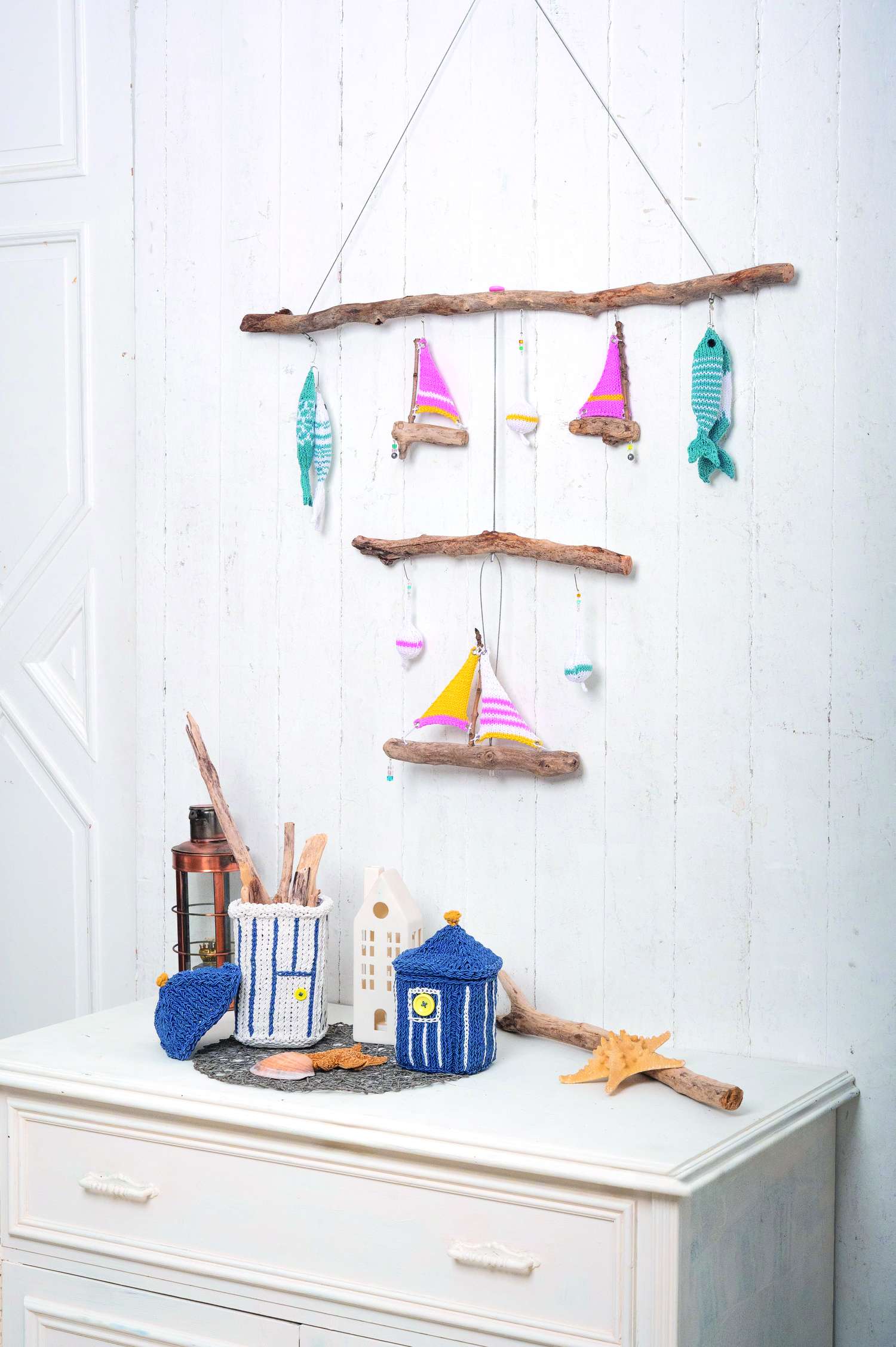 Buntes Mobile mit Segelbooten und Fischen. Handgemachte, gestrickte Körbe in Blau-Weiß. Küstennaher DIY-Stil.