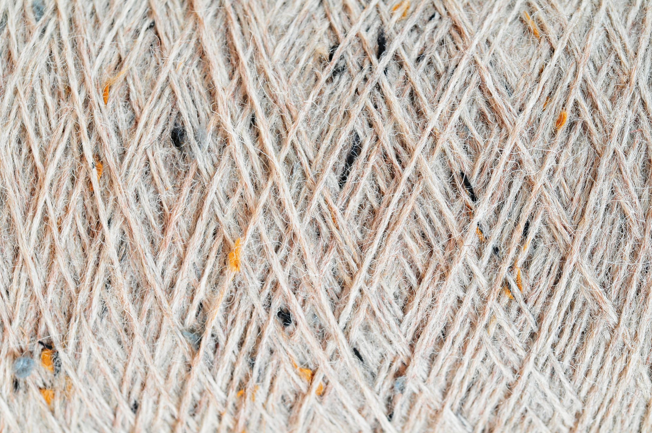 Beigefarbenes Garn mit schwarzen und orangenen Akzenten. Textil, handgemacht, DIY, kreativ.