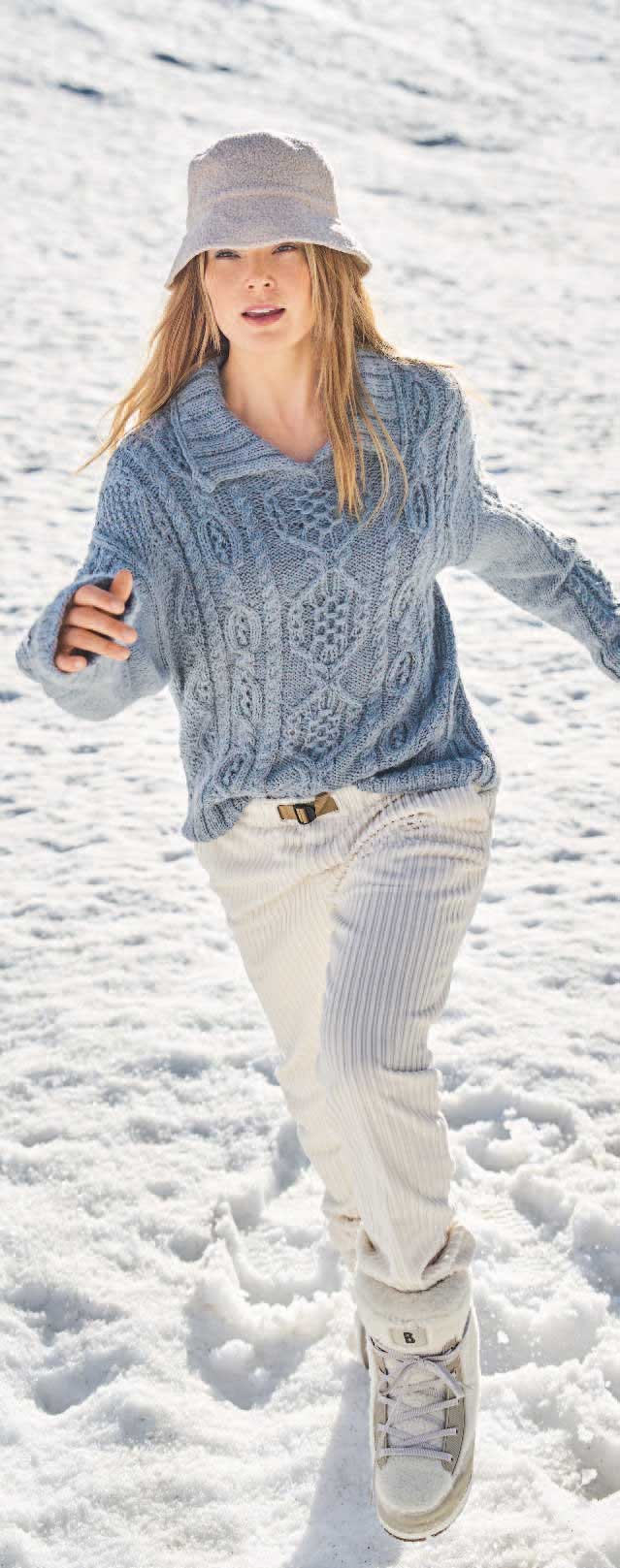 Modischer blauer Strickpullover mit komplexem Muster, kombiniert mit lässigem Eimerhut und weißen Schnürstiefeln.