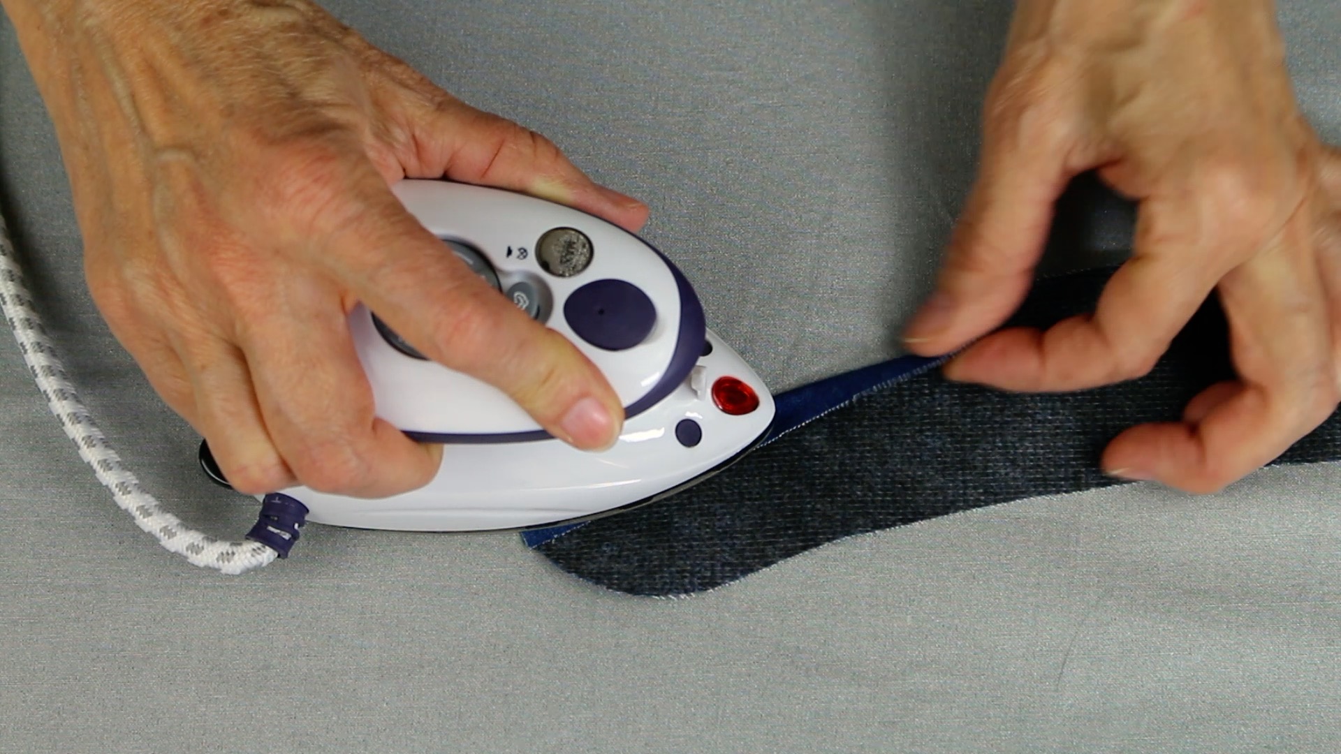 Kleidung bügeln: Blaues, fein gemustertes Band. Handarbeit, Detailorientierung, DIY-Akzent.