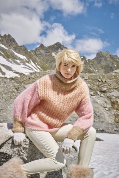 Modischer, handgemachter Pullover in Rosa-Nuancen, weiche Textur; cremefarbene Hose und Handschuhe.