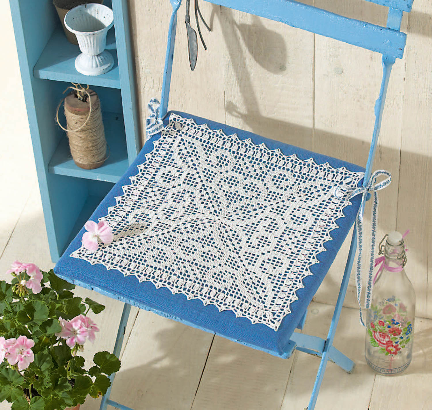 Weißes, handgefertigtes Häkelmuster auf blauer Fläche. Detailverliebte Handarbeit, Vintage-Stil.