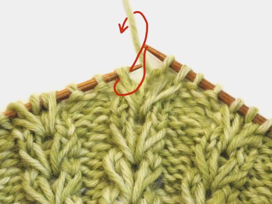 Handgestricktes Zopfmuster, grüne Nuancen auf Holznadeln, modisch und DIY, detailreich und kreativ.