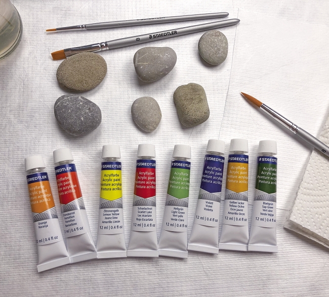 Bunte Acrylfarben-Tuben neben neutralen Steinen; ideal für DIY-Kunstprojekte. Lebendig, künstlerisch, Handarbeit.