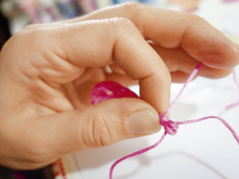 Hand fertigt Knoten mit pinkem Garn. DIY, handgefertigt, zart und kunstvoll. Modisch und einzigartig.