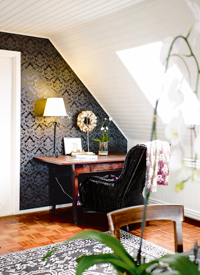 Samtiger schwarzer Stuhl, floral dekoriert; Wand in filigranem Barockmuster, stilvoll und modisch.