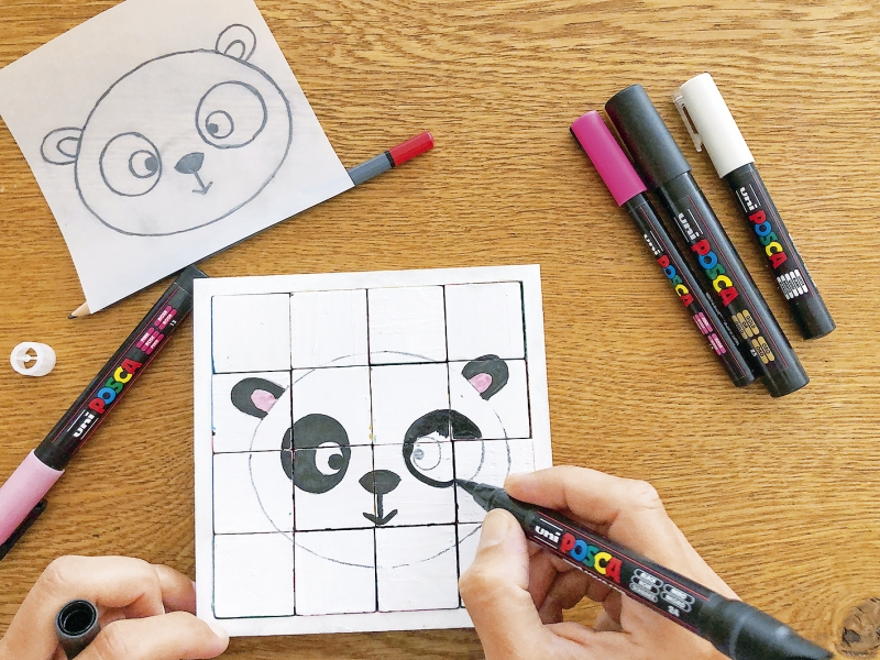 Handgezeichnetes Panda-Motiv auf Kacheln. Farbstifte in Schwarz, Rosa, Weiß. DIY, handgemacht, kunstvoll.