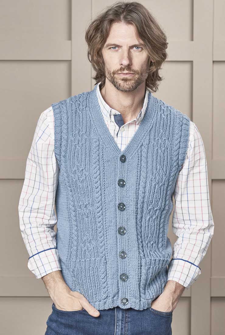 Blaue, handgemachte Strickweste mit Zopfmuster; kombiniert mit karierter Bluse; modisch und individuell.