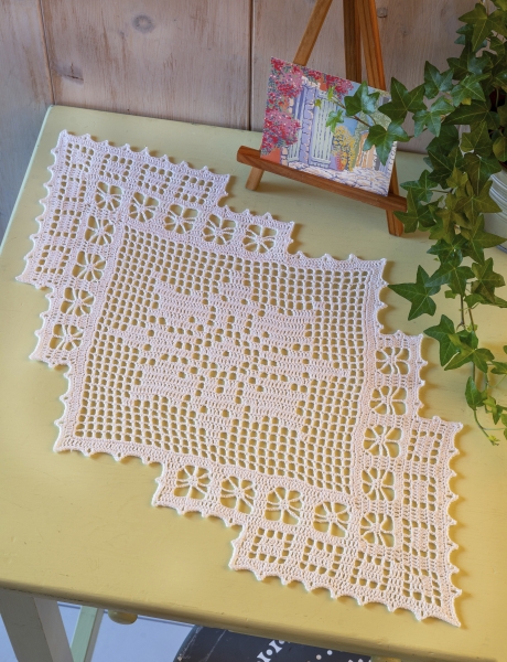 Weiße, handgefertigte Häkeldecke mit filigranem Spitzenmuster. Rechteckiger Schnitt, detailreiche Handarbeit, DIY-Stil.