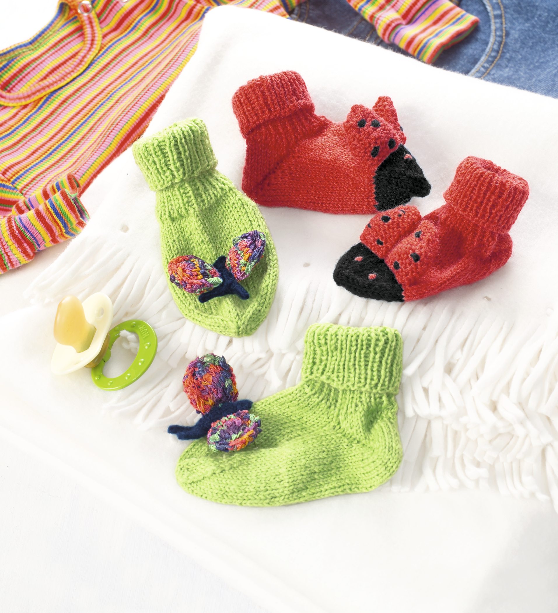 Bunte, handgemachte Babysocken: Grün mit Schmetterlingsmuster, Rot als Marienkäfer. Strickdesign, modisch und einzigartig.