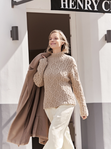 Zopfmusterpullover in Beige, grob gestrickt, modisch kombiniert mit lockerem Mantel. Elegante Naturtöne, zeitlos.