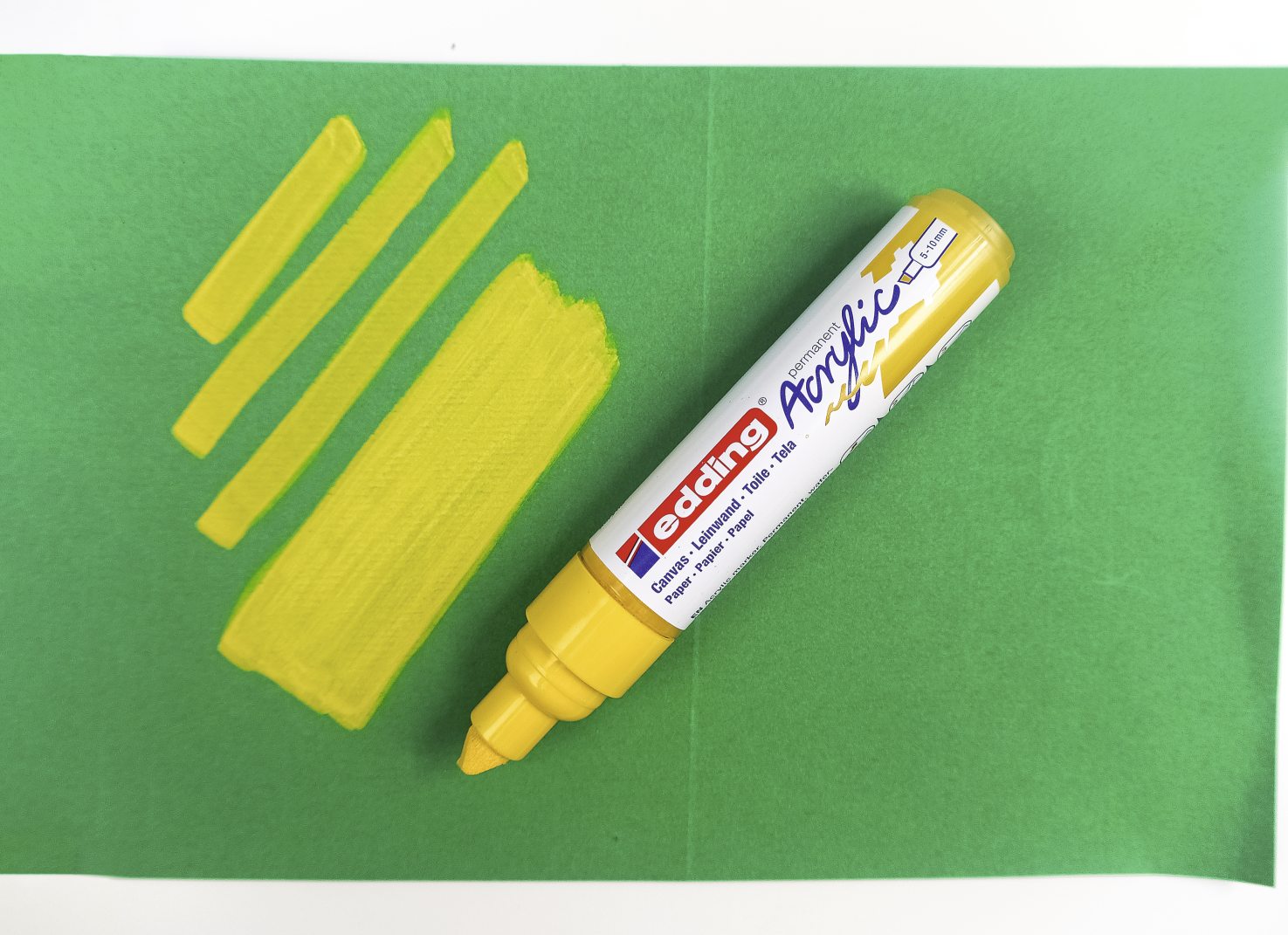 Gelber Marker auf grünem Papier, kräftige Linien, lebhafte Farbgebung, kreative DIY-Projekte.